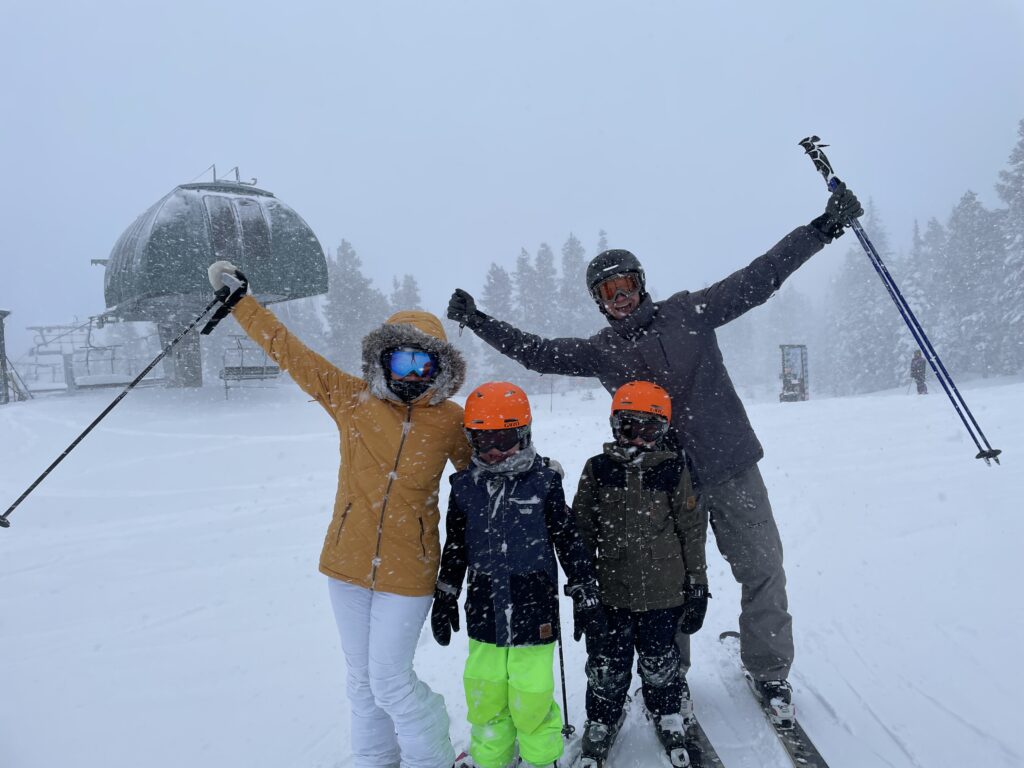 Family celebrating skiing together at the base of a ski slope in the snow