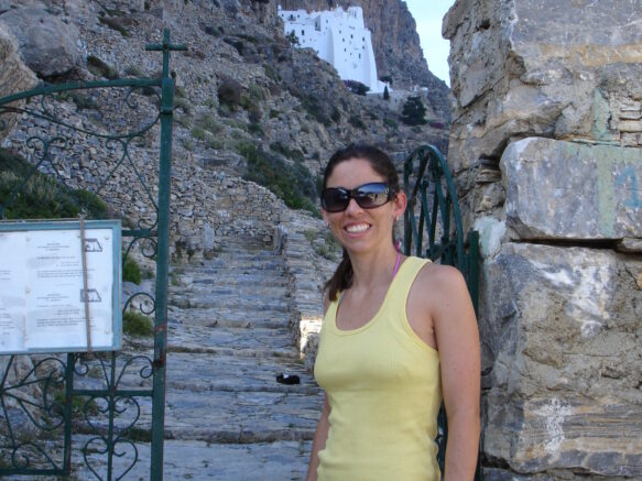 Woman in a yellow tank and camo skirt standing in Amorgos Greece