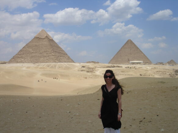Woman in a black dress and white pants standing in front of pyramids of cairo Egypt