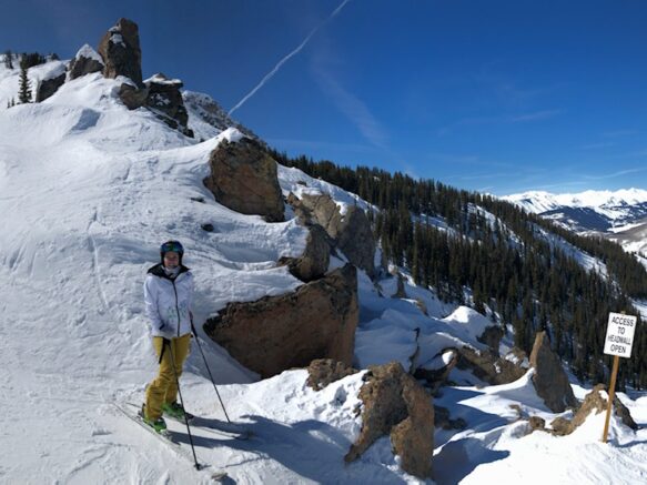 Woman standing on the side of a mountain at the top of a ski slope