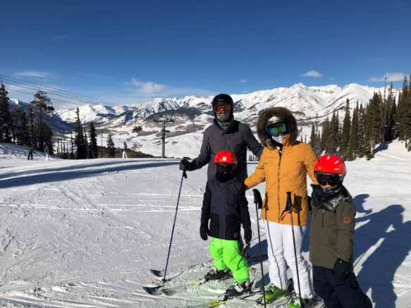 Family in ski outfits ready to go snow skiing at the base of the mountain