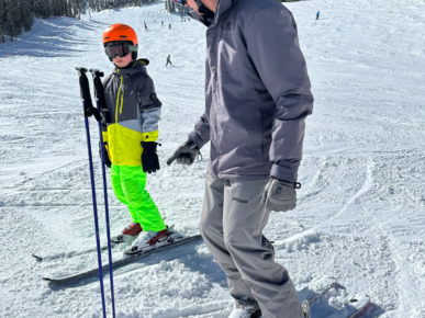 Dad teaching his son how to ski on the slopes